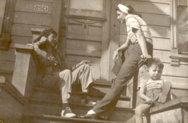 Julia Boyd sitting on steps, talking to Florence Boyd with Florence’s son Frank sitting on a low wall